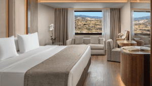 Elegant hotel room with a large bed, sofa, and panoramic window views.